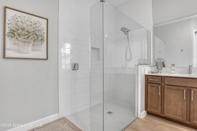 bathroom featuring a tile shower, vanity, and hardwood / wood-style flooring