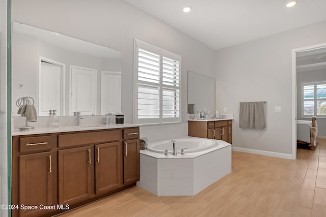 bathroom with vanity, a relaxing tiled tub, and wood-type flooring