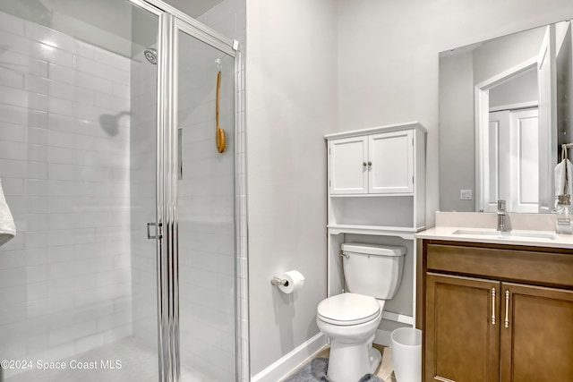 bathroom featuring vanity, toilet, and a shower with shower door