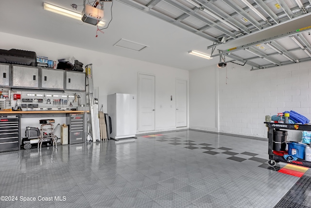 garage featuring a workshop area, a garage door opener, and fridge