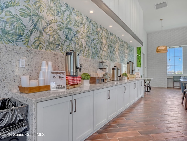 kitchen featuring light stone countertops, white cabinetry, and wood-type flooring