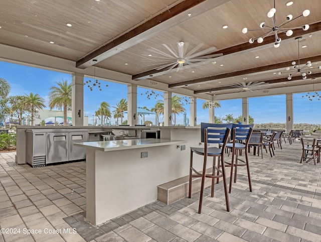 view of patio with ceiling fan, a bar, and exterior kitchen