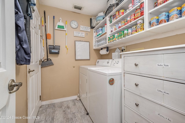 laundry room featuring light wood-type flooring, a textured ceiling, and independent washer and dryer