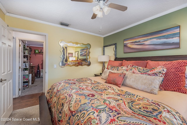 bedroom with ceiling fan, ornamental molding, a textured ceiling, a closet, and hardwood / wood-style flooring