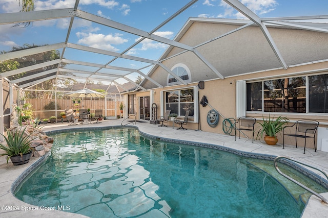 view of swimming pool featuring glass enclosure and a patio area