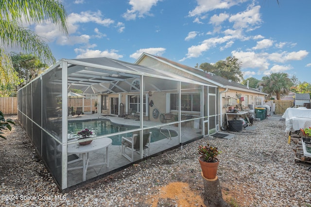 back of property featuring a patio, a fenced in pool, and a lanai