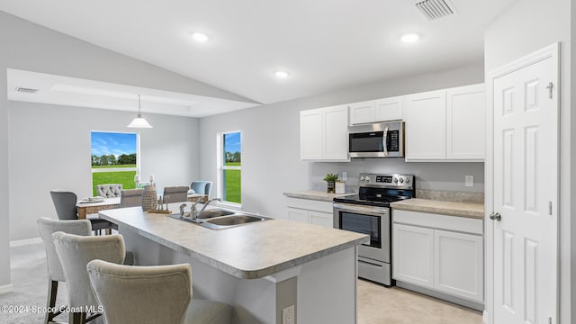 kitchen with sink, hanging light fixtures, an island with sink, white cabinetry, and stainless steel appliances