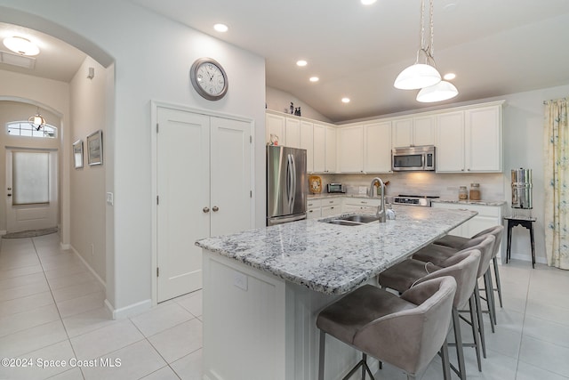 kitchen with stainless steel appliances, white cabinetry, a kitchen island with sink, and lofted ceiling