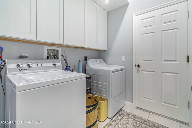 laundry area with washer and dryer, light tile patterned floors, and cabinets