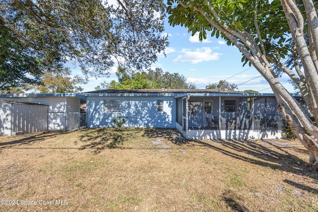 rear view of property featuring a sunroom and a lawn