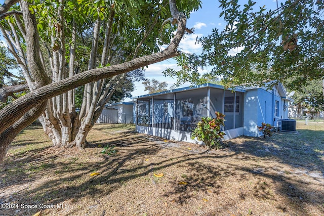 back of property with central AC and a sunroom