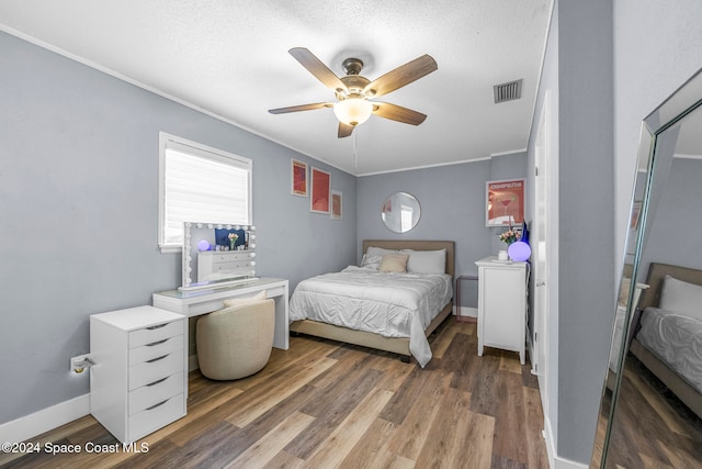 bedroom with a textured ceiling, ceiling fan, crown molding, and dark wood-type flooring