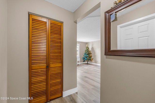 corridor with a textured ceiling and light hardwood / wood-style flooring