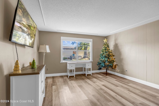 office space with wooden walls, light hardwood / wood-style flooring, and a textured ceiling