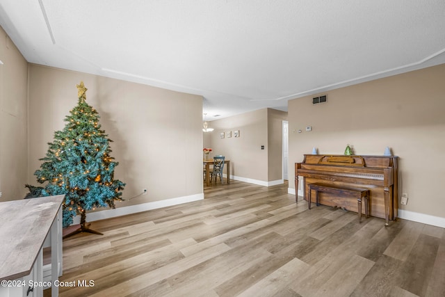 misc room with light hardwood / wood-style floors and an inviting chandelier