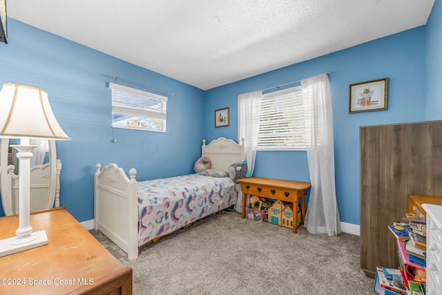 bedroom featuring multiple windows, light carpet, and a textured ceiling