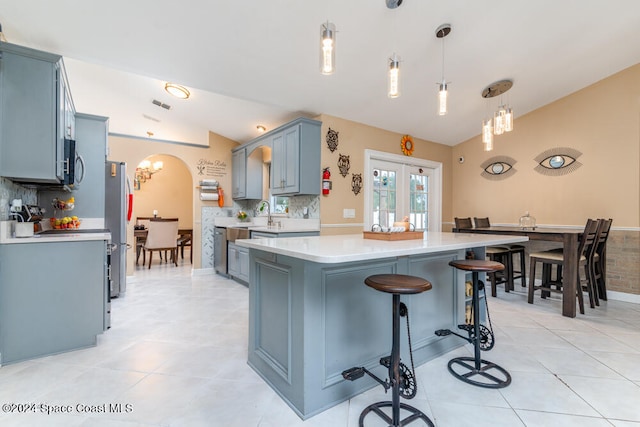 kitchen with lofted ceiling, hanging light fixtures, light tile patterned floors, and stainless steel appliances