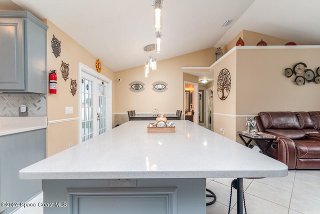 kitchen featuring pendant lighting, tasteful backsplash, lofted ceiling, and french doors