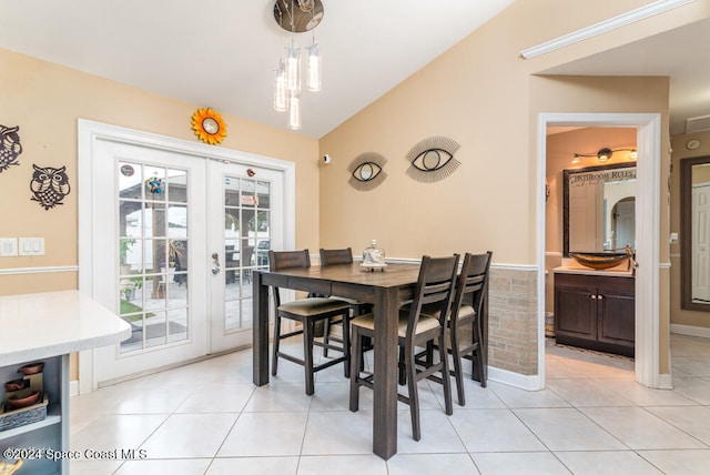 tiled dining space featuring french doors and vaulted ceiling