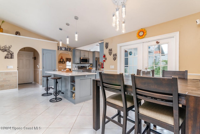 kitchen featuring pendant lighting, a center island, vaulted ceiling, gray cabinets, and appliances with stainless steel finishes