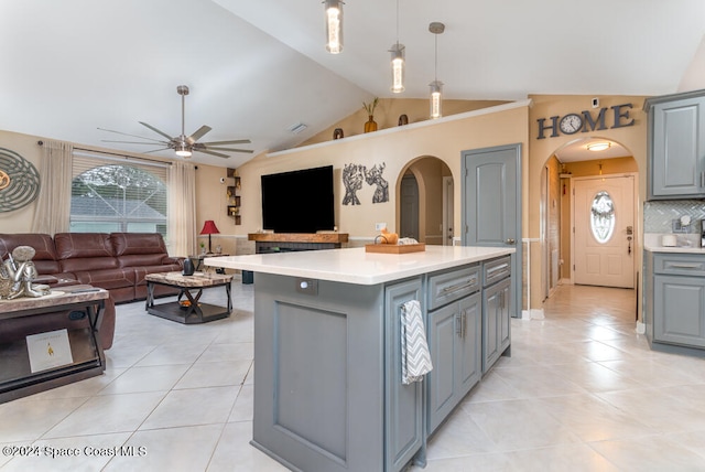 kitchen featuring decorative light fixtures, a center island, light tile patterned flooring, and vaulted ceiling