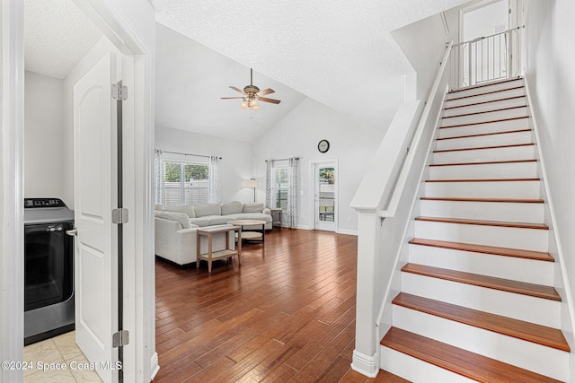 stairway featuring hardwood / wood-style floors, high vaulted ceiling, ceiling fan, a textured ceiling, and washer / dryer