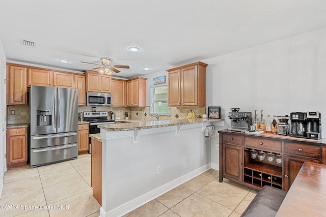 kitchen featuring kitchen peninsula, a kitchen breakfast bar, stainless steel appliances, and light stone countertops