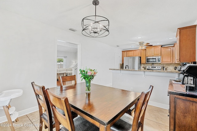 tiled dining space with ceiling fan with notable chandelier