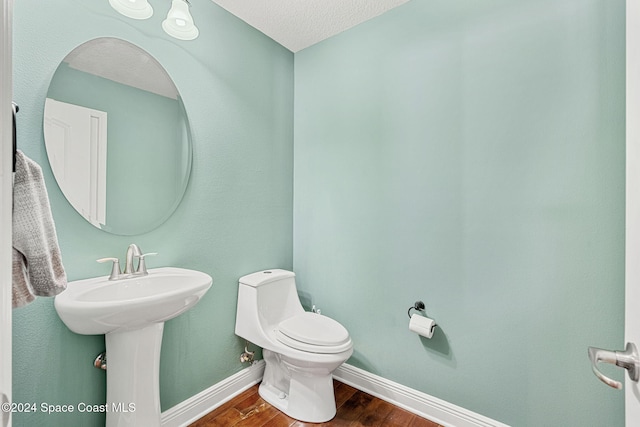 bathroom featuring a textured ceiling, hardwood / wood-style flooring, toilet, and sink