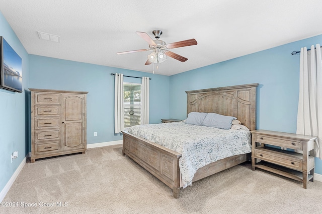 bedroom featuring ceiling fan, light colored carpet, and a textured ceiling