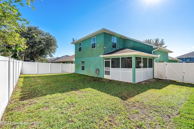 back of property featuring a lawn and a sunroom