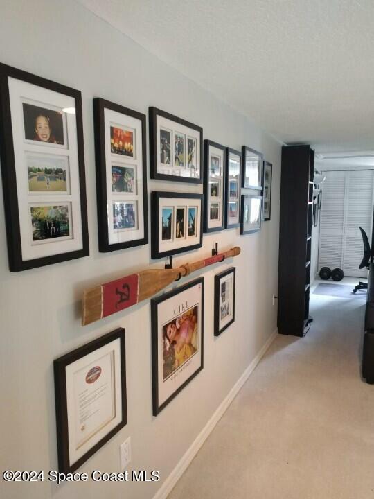 hallway with light colored carpet and a textured ceiling