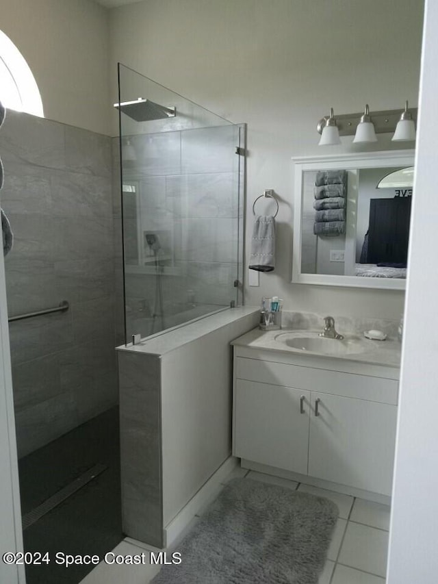 bathroom featuring a tile shower, tile patterned flooring, and vanity