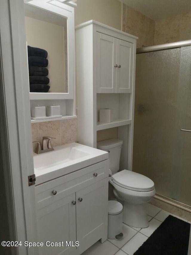 bathroom with tile patterned floors, vanity, a shower with shower door, and toilet