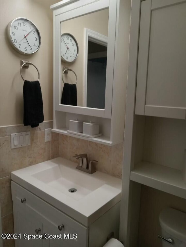 bathroom with vanity, toilet, tile walls, and tasteful backsplash