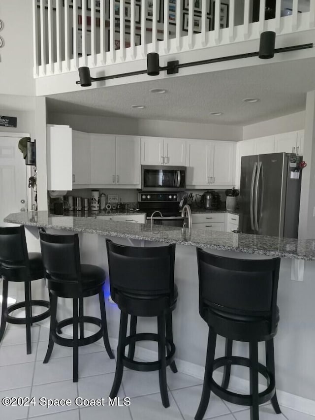 kitchen featuring white cabinets, appliances with stainless steel finishes, and a kitchen breakfast bar