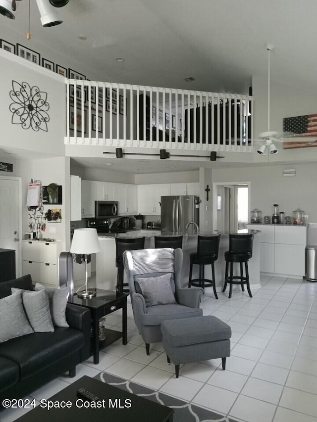 tiled living room with ceiling fan and a high ceiling