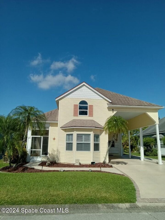 rear view of property featuring a carport and a lawn