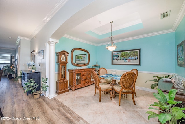 dining room with light hardwood / wood-style floors, a raised ceiling, ornamental molding, and decorative columns