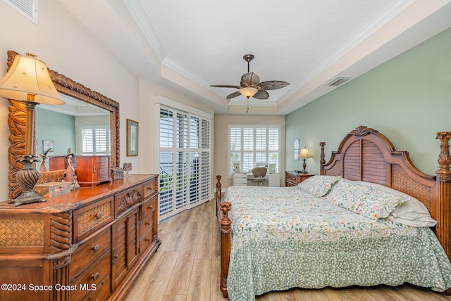 bedroom with light hardwood / wood-style floors, a raised ceiling, ceiling fan, and ornamental molding