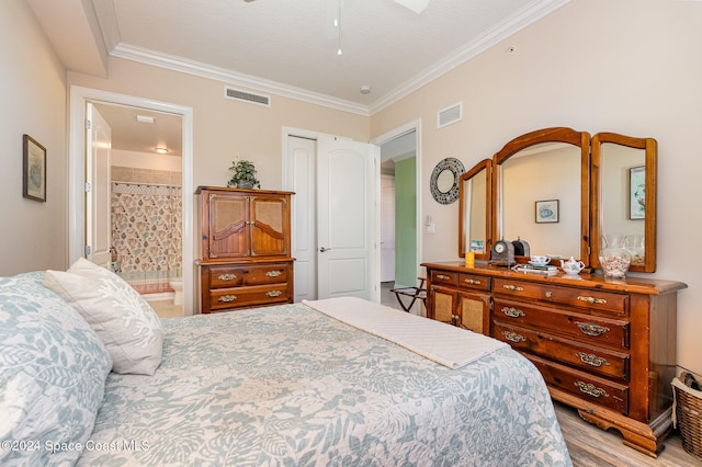 bedroom featuring ensuite bathroom, light hardwood / wood-style floors, ornamental molding, and ceiling fan