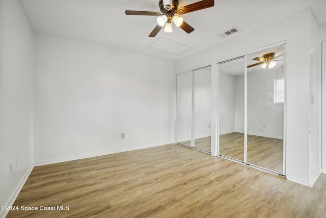 unfurnished bedroom with ceiling fan, wood-type flooring, and multiple closets