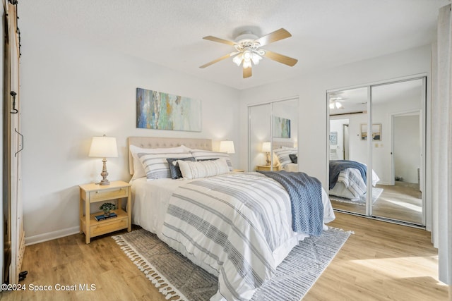 bedroom featuring a textured ceiling, light wood-type flooring, two closets, and ceiling fan