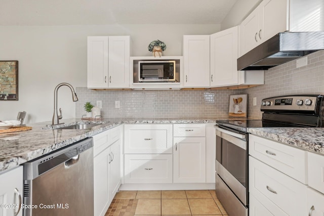 kitchen featuring sink, tasteful backsplash, light stone counters, white cabinets, and appliances with stainless steel finishes