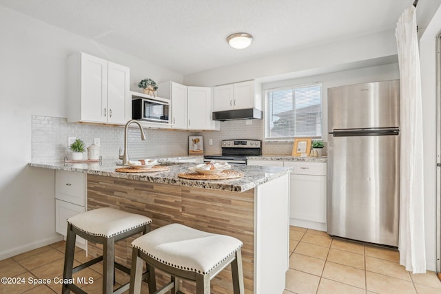 kitchen featuring white cabinets, stainless steel appliances, and light stone counters