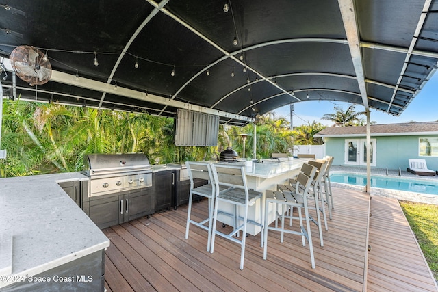 wooden deck featuring a bar, an outdoor kitchen, and area for grilling