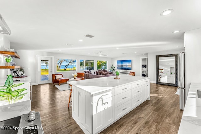 kitchen with a kitchen bar, light stone countertops, a kitchen island, dark hardwood / wood-style floors, and white cabinetry