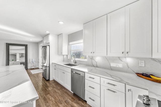 kitchen with white cabinets, sink, dark hardwood / wood-style floors, appliances with stainless steel finishes, and light stone counters