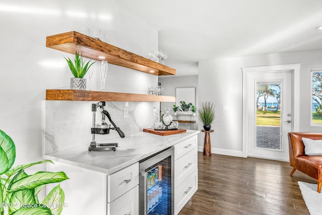 kitchen featuring white cabinets, dark hardwood / wood-style flooring, light stone counters, and beverage cooler