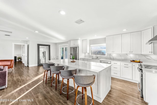 kitchen featuring a center island, white cabinets, stainless steel appliances, and wood-type flooring